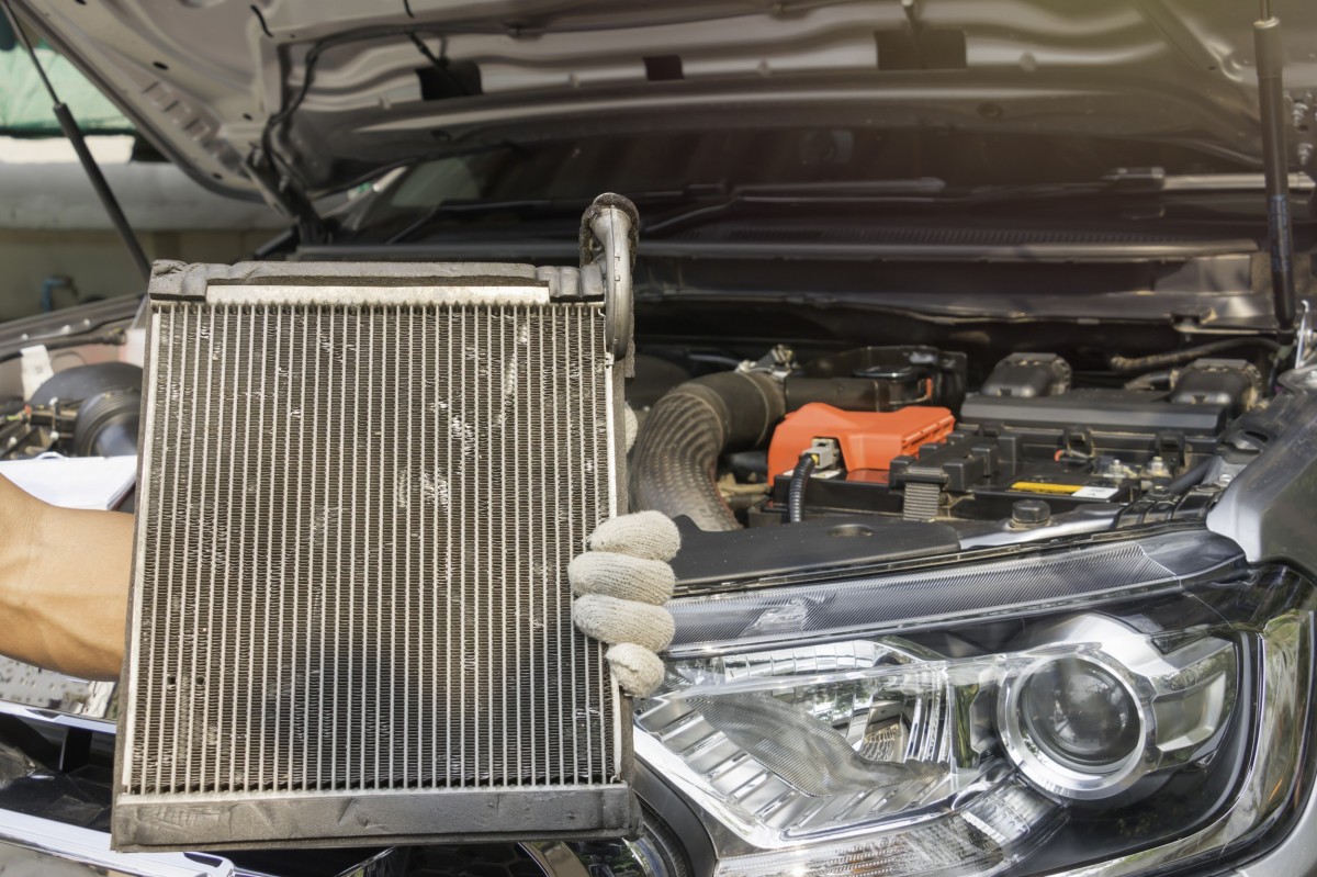 hand holding radiator in front of car with hood up