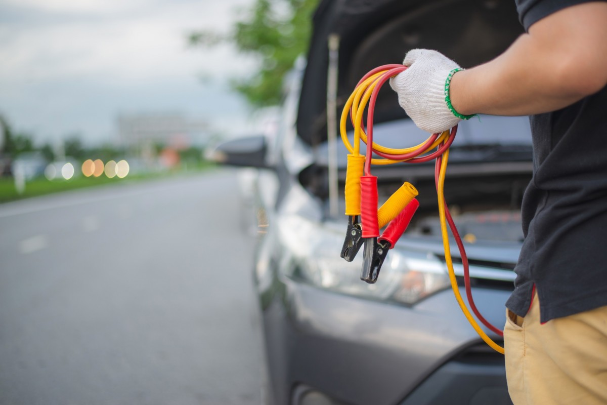 jumper cables being held by person in front of car 