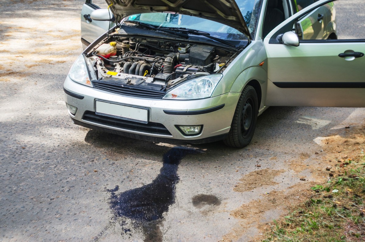 car with hood up and puddle underneath of it
