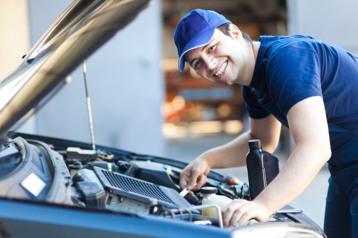 technician smiling under the hood of the car